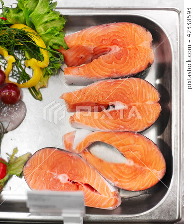 salmon fish fillet in metal tray on ice at grocery 42338593