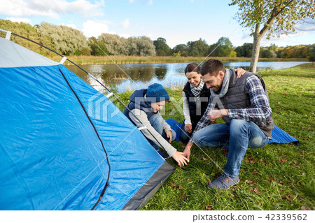 happy parents and son setting up tent at campsite 42339562