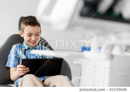 happy kid patient with tablet pc at dental clinic happy kid patient with tablet pc at dental clinic 42339696