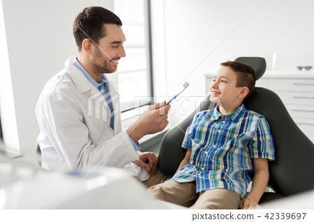 dentist with toothbrush and kid patient at clinic dentist with toothbrush and kid patient at clinic 42339697