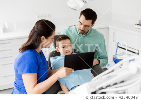 dentist showing tablet pc to kid at dental clinic dentist showing tablet pc to kid at dental clinic 42340049