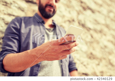 close up of man with smartphone at stone wall 42340129