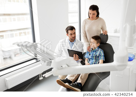 dentist showing tablet pc to kid at dental clinic dentist showing tablet pc to kid at dental clinic 42340254