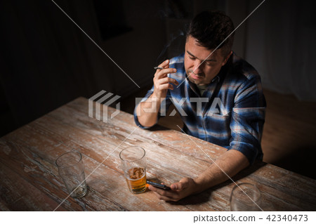 man with cellphone drinking alcohol and smoking man with cellphone drinking alcohol and smoking 42340473