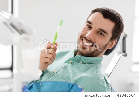 smiling man with toothbrush at dental clinic smiling man with toothbrush at dental clinic 42340504