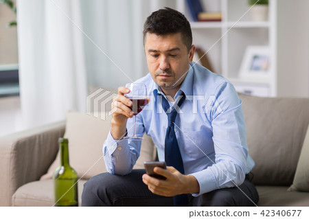 drunk man with alcohol and smartphone at home 42340677