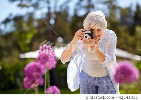 senior woman with camera photographing flowers 42341018