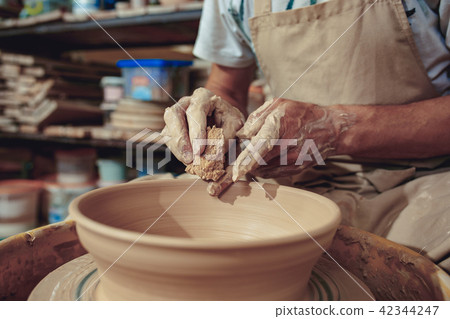 Creating a jar or vase of white clay close-up. Master crock. Man hands making clay jug macro. 42344247
