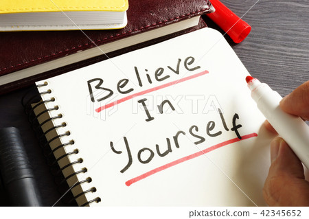 Man is writing Believe In Yourself in a note. Man is writing Believe In Yourself in a note. 42345652