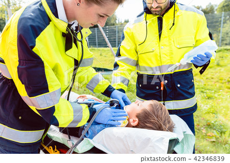 Paramedics measuring blood pressure of injured boy 42346839