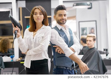 Two hairstylers posing standing in modern spacy beaty salon. Two hairstylers posing standing in modern spacy beaty salon. 42347876