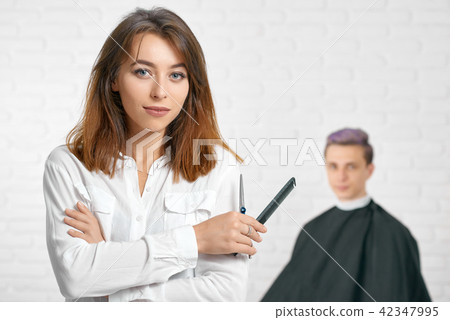 Woman hairstylist looking at camera holding comb and scissors. 42347995