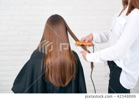Model sitting while hairstyling in beaty salon with white brick walls. 42348009
