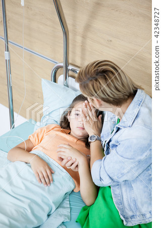 Mother taking care of her daughter in hospital room 42348727