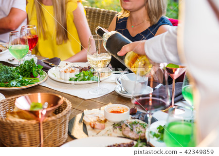 Professional waiter in uniform serving wine to guests of event. Catering or celebration concept Professional waiter in uniform serving wine to guests of event. Catering or celebration concept 42349859