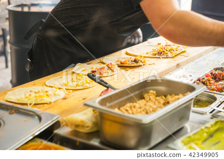 Chef's hands preparing mexican tacos at a street food market, festival, event. Process cooking Chef's hands preparing mexican tacos at a street food market, festival, event. Process cooking 42349905
