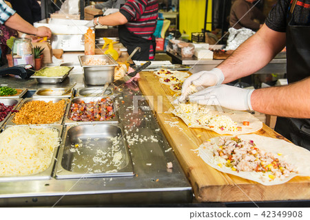 Chef's hands preparing mexican tacos at a street food market, festival, event. Process cooking Chef's hands preparing mexican tacos at a street food market, festival, event. Process cooking 42349908