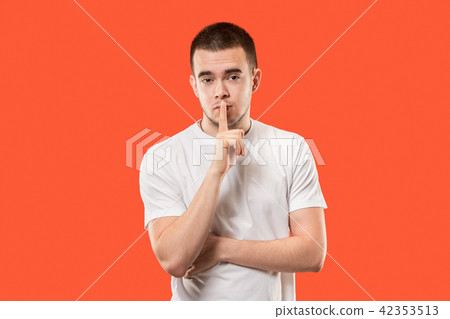 The young man whispering a secret behind her hand over orange background The young man whispering a secret behind her hand over orange background 42353513