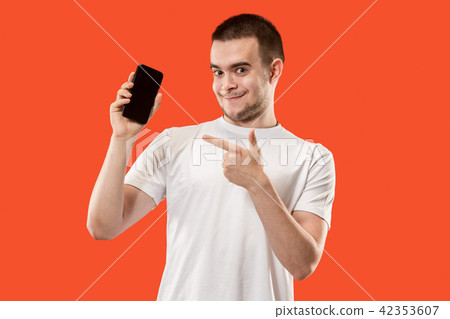 The happy man showing at empty screen of mobile phone against orange background. 42353607