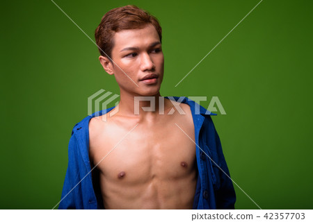 Young Asian businessman wearing blue shirt fully unbuttoned Young Asian businessman wearing blue shirt fully unbuttoned 42357703