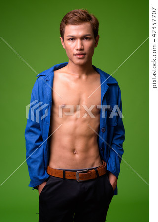 Young Asian businessman wearing blue shirt fully unbuttoned Young Asian businessman wearing blue shirt fully unbuttoned 42357707