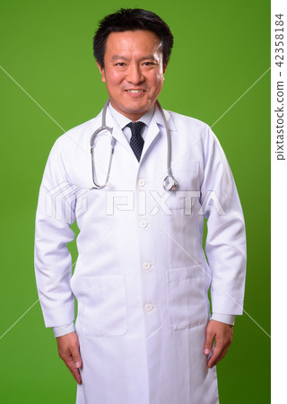 Mature Japanese man doctor against green background 42358184