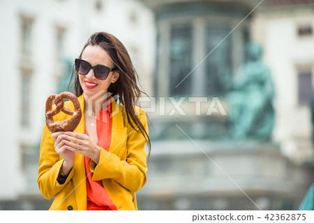 Beautiful young woman holding pretzel and relaxing in park Beautiful young woman holding pretzel and relaxing in park 42362875