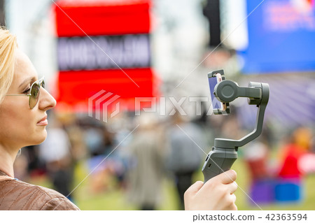 the girl with the phone on the stabilizer leads the videoblog. She takes herself to the camera 42363594