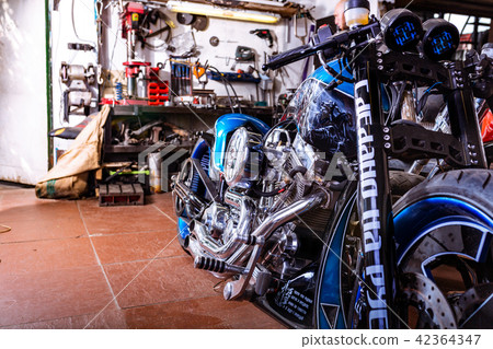 Cropped close up shot of beautiful and custom made motorcycle in the workshop Cropped close up shot of beautiful and custom made motorcycle in the workshop 42364347
