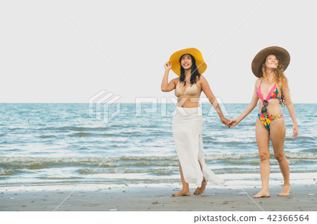 Happy women go sunbathing at sand beach in summer. 42366564