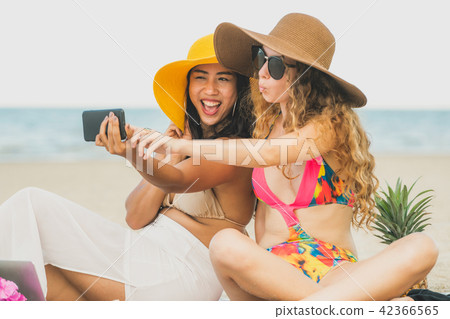Happy women taking photo on sand beach in summer. 42366565