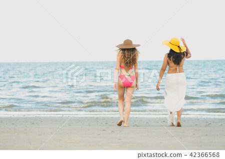 Happy women go sunbathing at sand beach in summer. Happy women go sunbathing at sand beach in summer. 42366568
