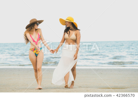 Happy women go sunbathing at sand beach in summer. Happy women go sunbathing at sand beach in summer. 42366570