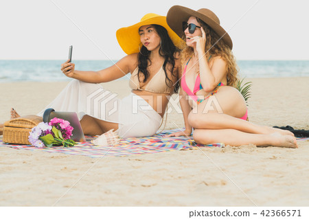 Happy women taking photo on sand beach in summer. Happy women taking photo on sand beach in summer. 42366571