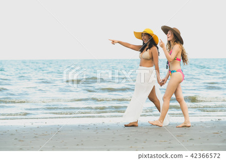 Happy women go sunbathing at sand beach in summer. Happy women go sunbathing at sand beach in summer. 42366572