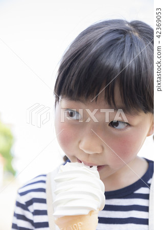 A girl who eats soft cream at an amusement park 42369053