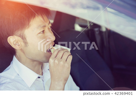 A businessman eating a sandwich in a car 42369401