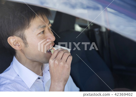 A businessman eating a sandwich in a car A businessman eating a sandwich in a car 42369402