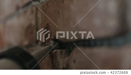 closeup of worker filling seam between bricks with mortar from sealant gun 42372689