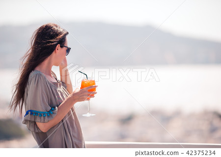 Young happy woman in outdoor cafe with tasty drink. Young happy woman in outdoor cafe with tasty drink. 42375234