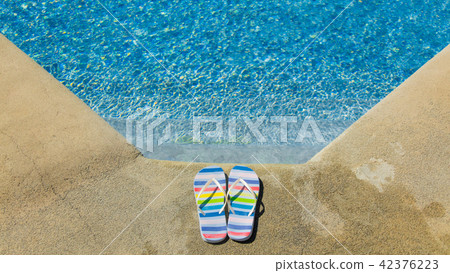 Colored summer sandals near blue pool Colored summer sandals near blue pool 42376223