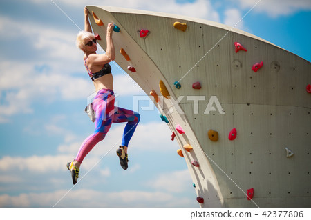 Photo from side of sports girl in leggings hanging on wall for climbing against blue sky Photo from side of sports girl in leggings hanging on wall for climbing against blue sky 42377806