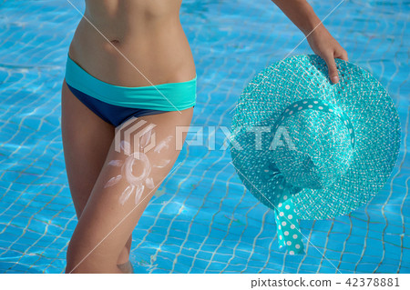 Sunscreen and beautiful female legs in the pool with a picture of the sun on his leg, conceptual Sunscreen and beautiful female legs in the pool with a picture of the sun on his leg, conceptual 42378881