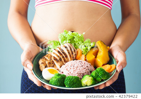 Fitness girl holding healthy food on dish. 42379422