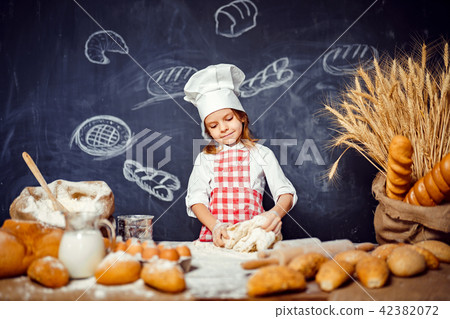 Adorable little girl in chef hat making dough Adorable little girl in chef hat making dough 42382072