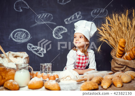 Adorable little girl in chef hat making dough Adorable little girl in chef hat making dough 42382130
