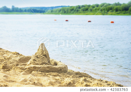 Sand castle on the shore, blue water. Summer, beach, sunny day 42383763
