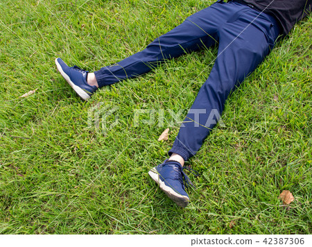 Man laying down on grass relaxing taking it easy Man laying down on grass relaxing taking it easy 42387306