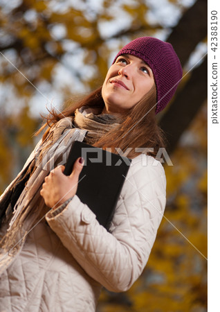 Positive student with book in hands in the fall park Positive student with book in hands in the fall park 42388190