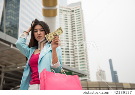 Sad shopaholic girl look at one dollar Sad shopaholic girl look at one dollar 42389157